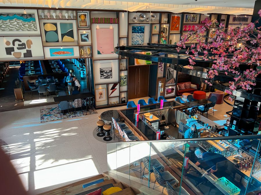 Intérieur maximaliste du Wave Hotel à Lake Nona, Orlando, avec mur de cadres éclectiques, mobilier coloré et décor dense.
