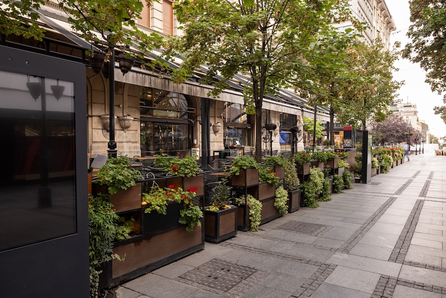 Terrasse de restaurant ombragée et végétalisée illustrant l’architecture du frais et le confort d’été en milieu urbain.
